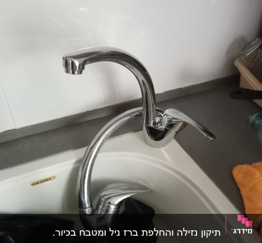 ברז מטבח עם כיור לבן ושקית שחורה